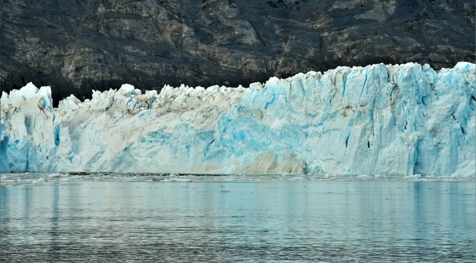 The long, low tidewater face of a Prince William Sound glacier seen across calm water