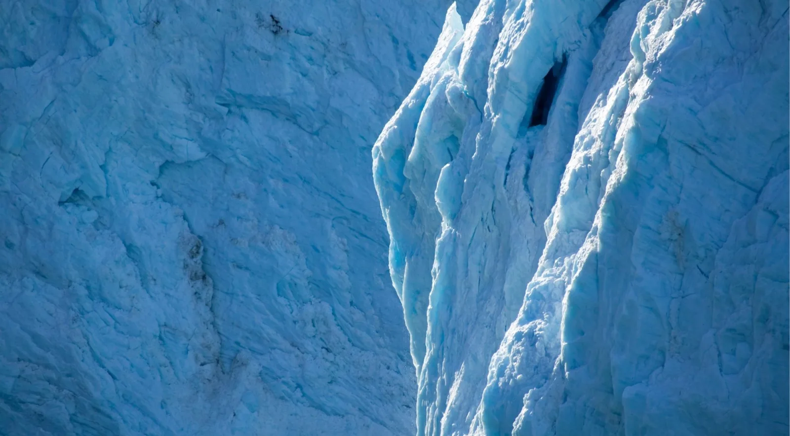 Close view of fractured blue ice and meltwater channels on a glacier face