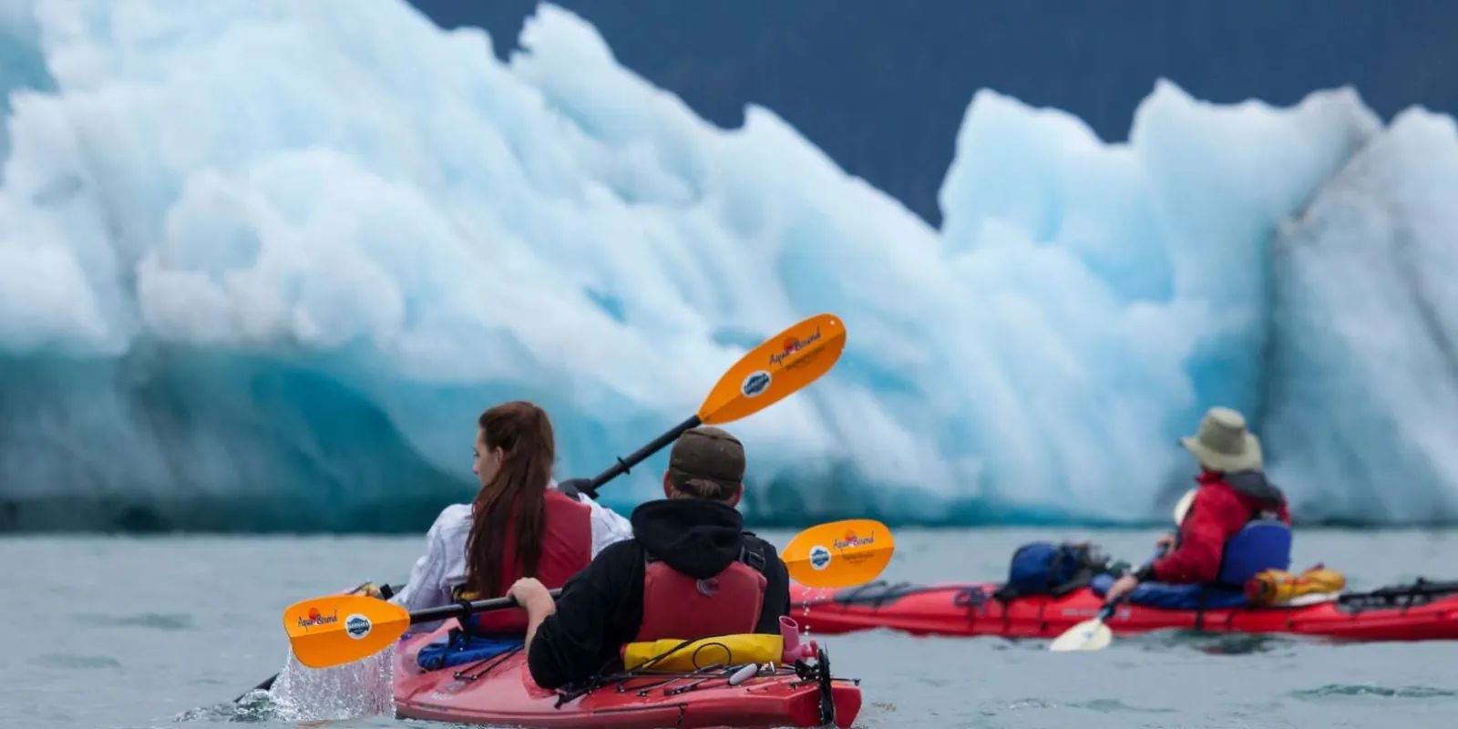 Kayakers paddling in front of a wall of stranded icebergs in Columbia Bay